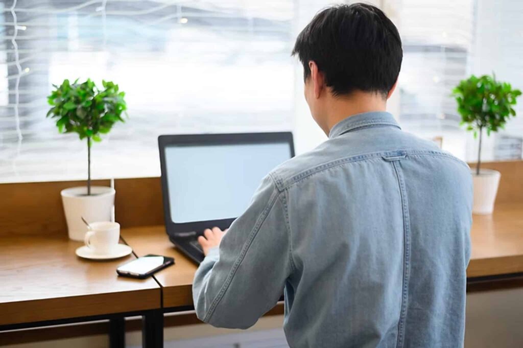 Professional working on a laptop in a modern workspace, representing duties typical for executive administrative and assistant roles.
