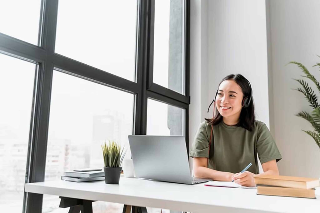 Remote receptionist working with a headset at a laptop, illustrating what is a remote receptionist in a modern home office setup