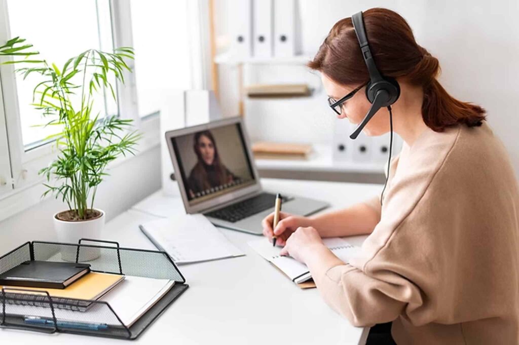 Woman wearing headset taking notes during a video call, illustrating the ultimate guide to hiring virtual assistants in 2025.